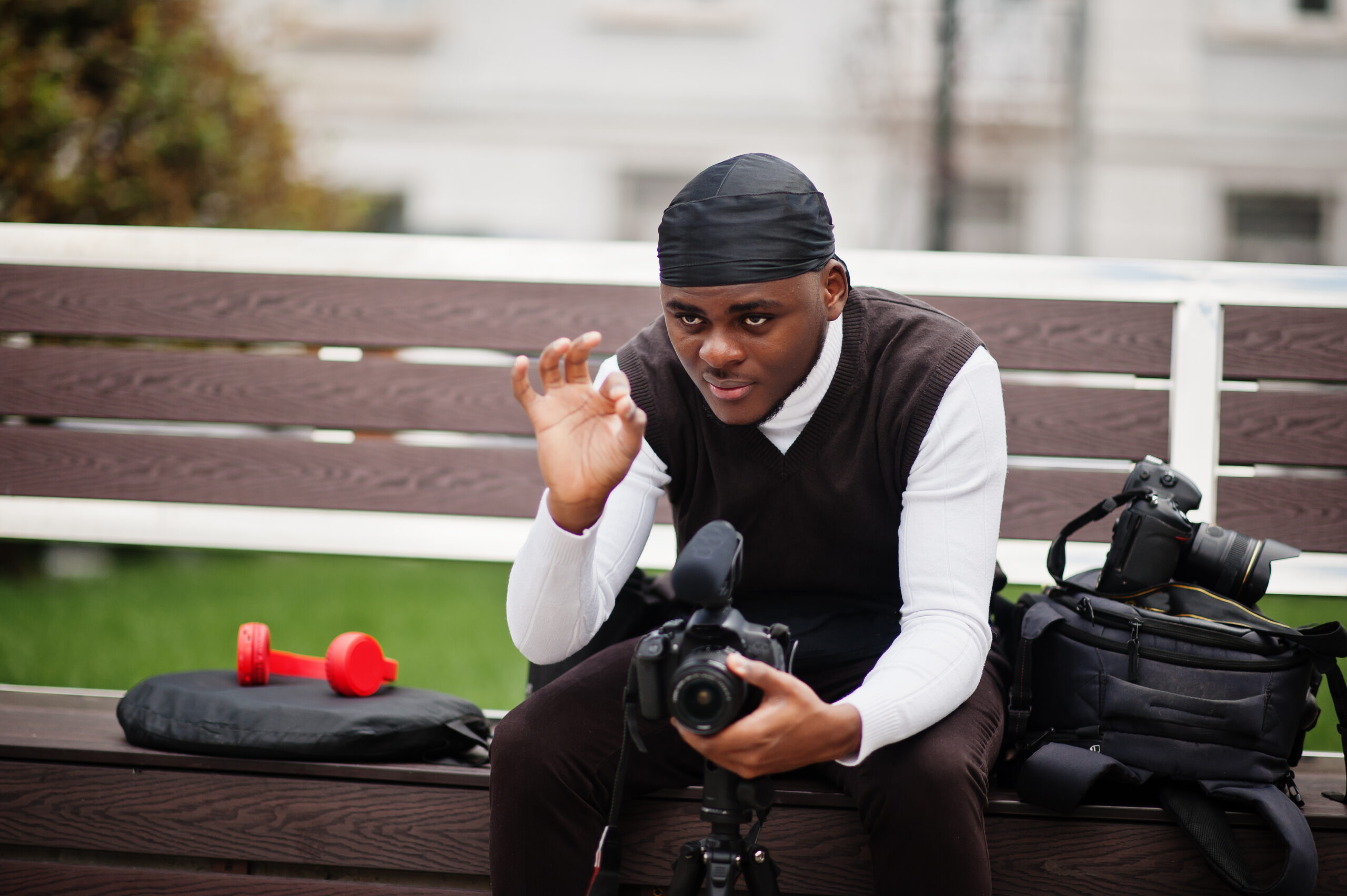 Young professional african american videographer holding professional camera with pro equipment. Afro cameraman wearing black duraq making a videos.